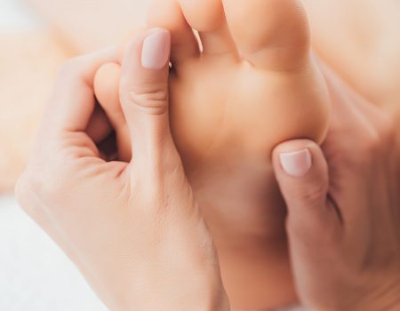 cropped view of masseur doing foot massage to adult woman in spa
